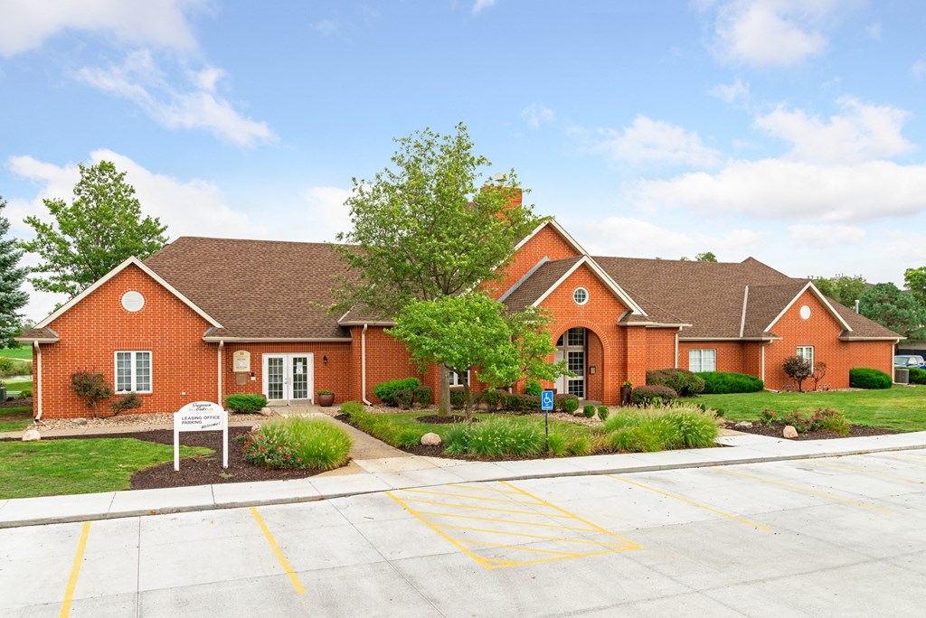 a red brick house with a driveway and a tree in front of it