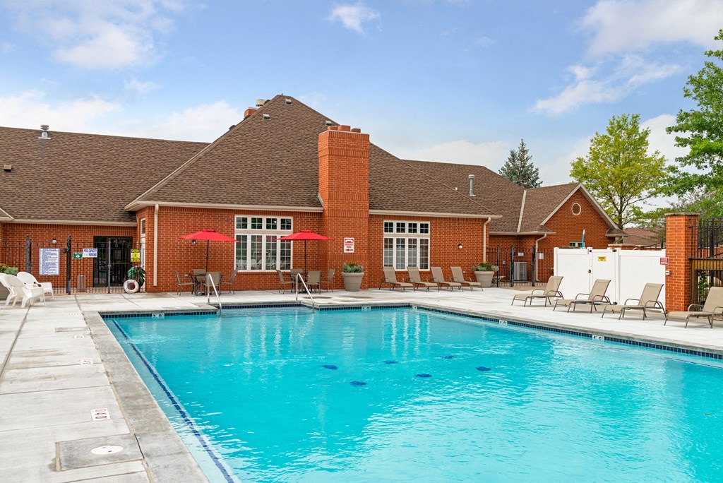 a swimming pool in front of a brick house with a pool