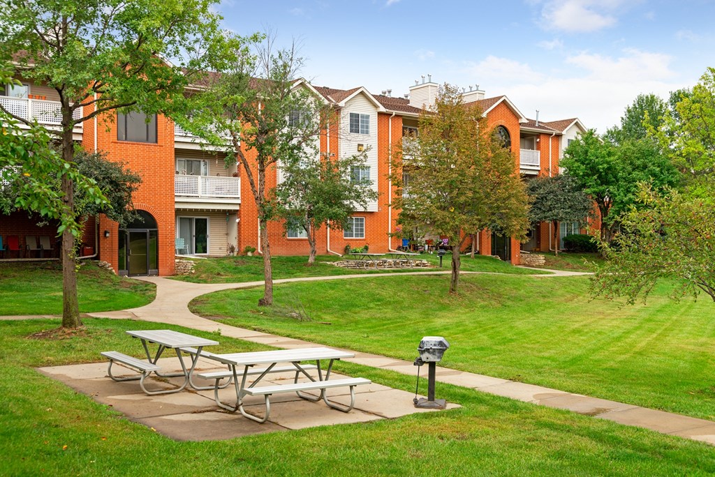 a park with picnic tables in front of an apartment building