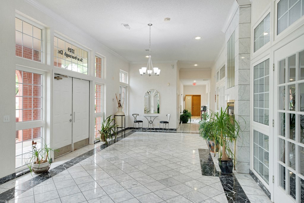 the lobby of an office building with large windows and a tiled floor