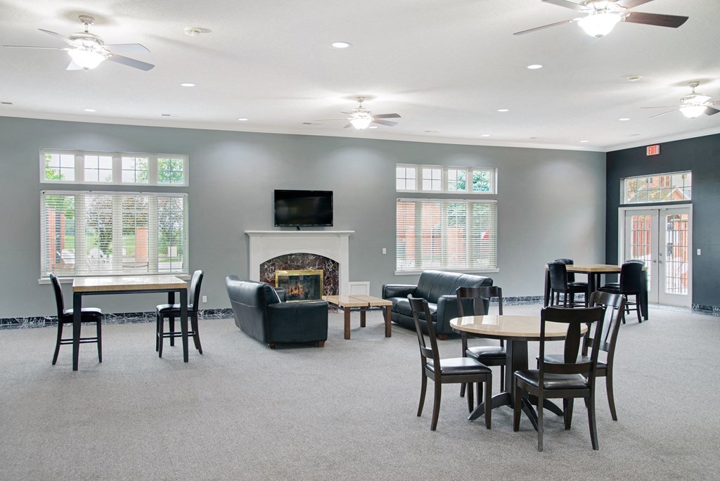 an empty living room with chairs and tables and a fireplace