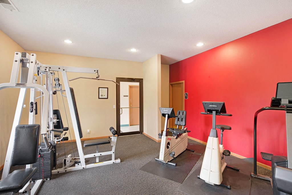 a gym with exercise equipment and a red wall