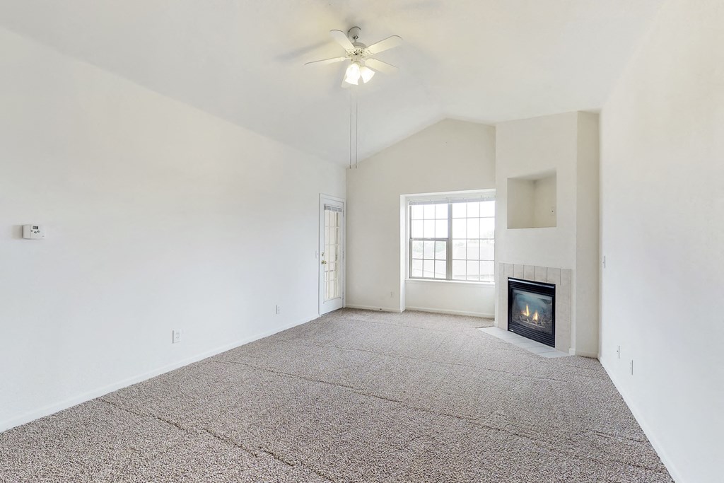 an empty living room with a fireplace and a ceiling fan