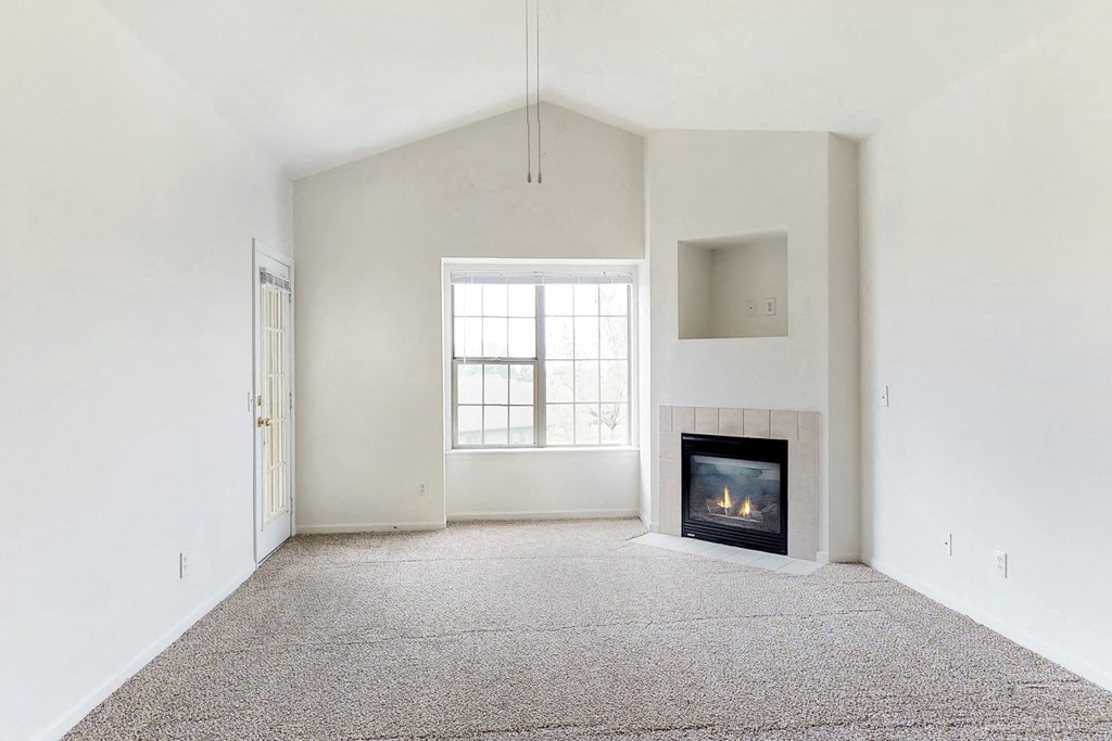 an empty living room with a fireplace and a window