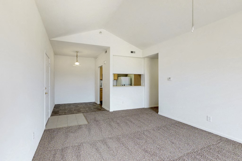 an empty living room with white walls and a tile floor