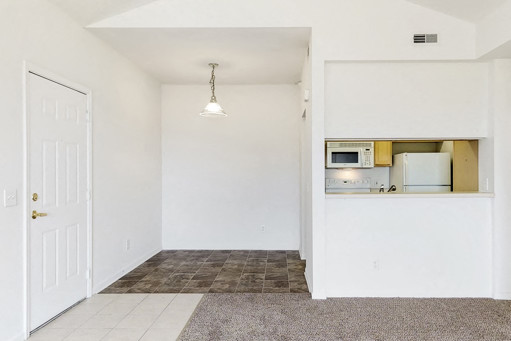 an empty kitchen and living room with a white door