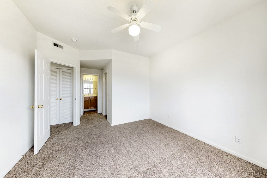an empty room with white walls and a ceiling fan