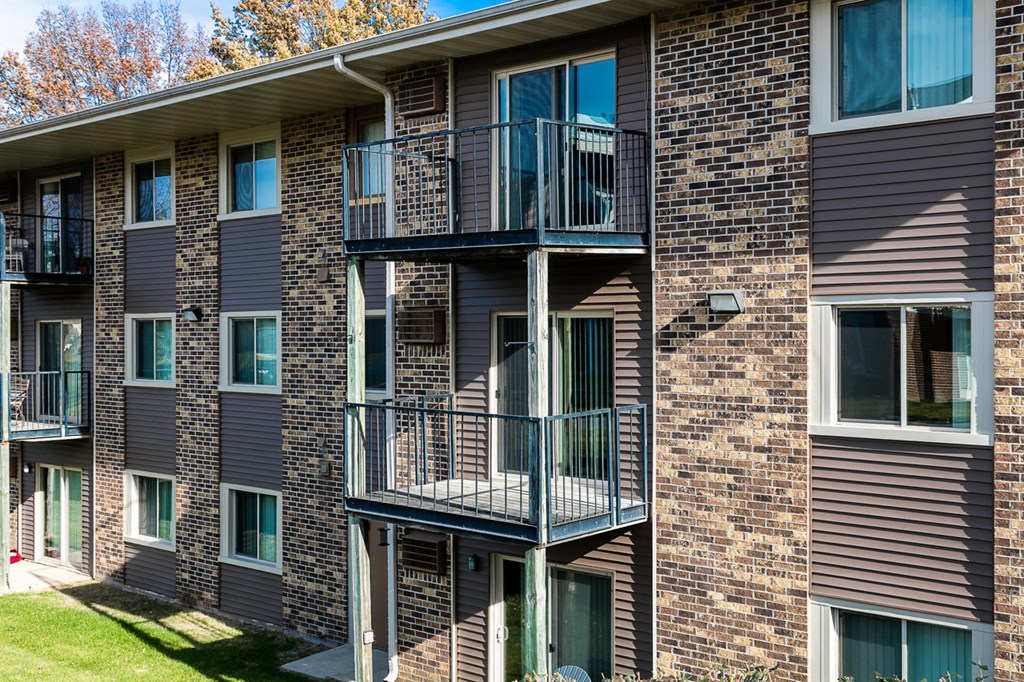 a brick apartment building with balconies and a lawn
