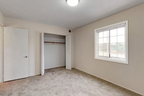 an empty bedroom with a closet and a window
