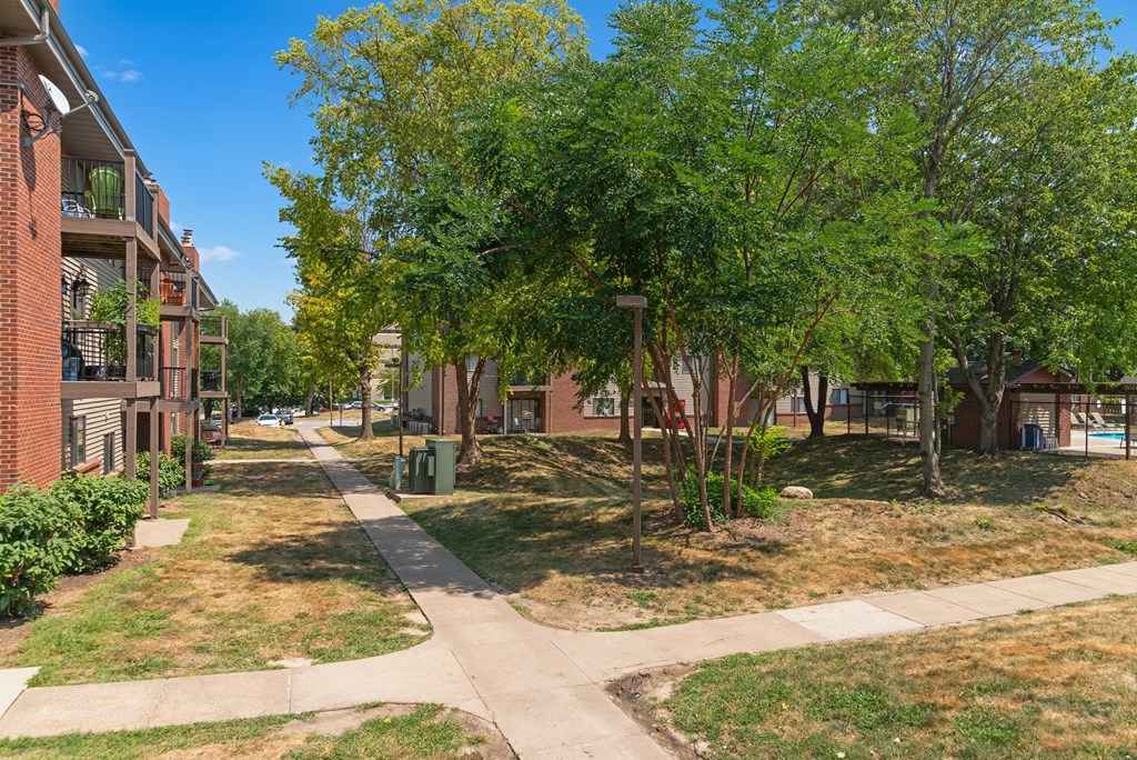 a city street with sidewalks and trees in front of apartment buildings