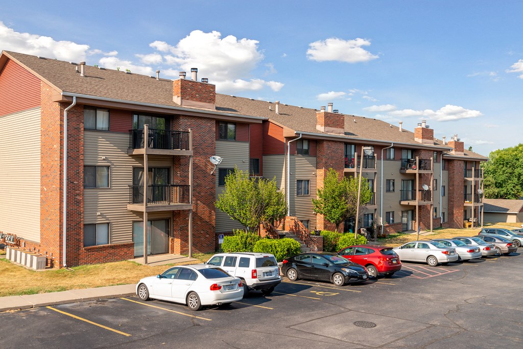 an apartment building with cars parked in a parking lot