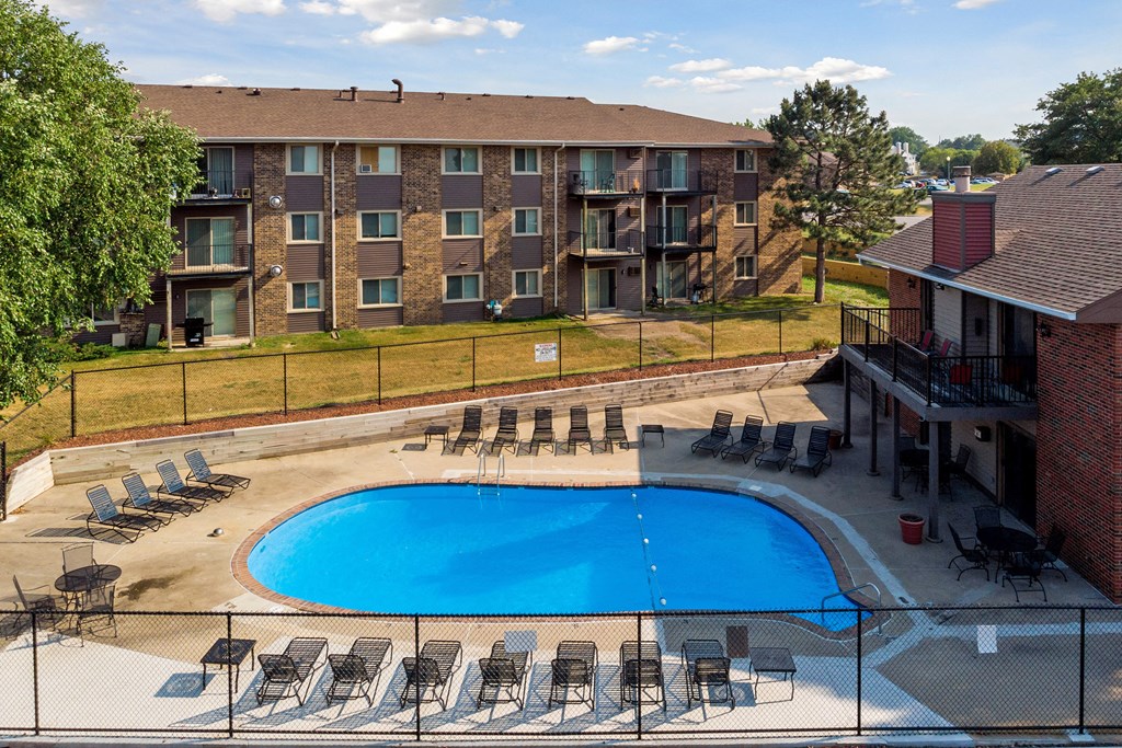 an aerial view of a pool with chairs and a building