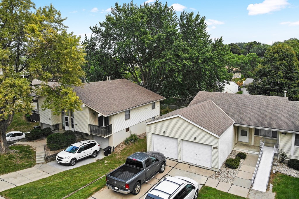 an aerial view of two houses with cars parked in the driveway