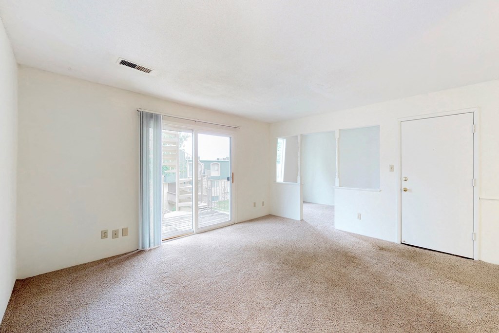 an empty living room with a door to a balcony