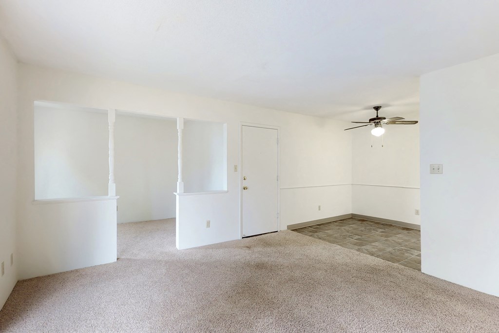 an empty living room with white walls and a ceiling fan
