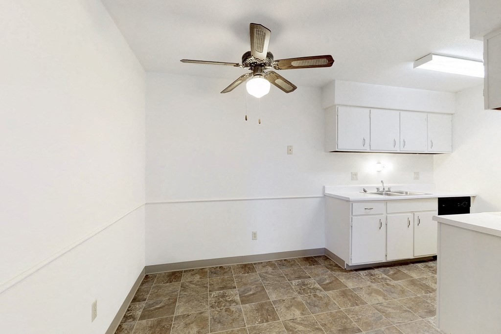 an empty kitchen with a ceiling fan and a sink