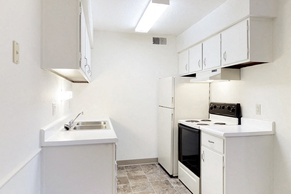 an empty kitchen with white cabinets and a stove and refrigerator