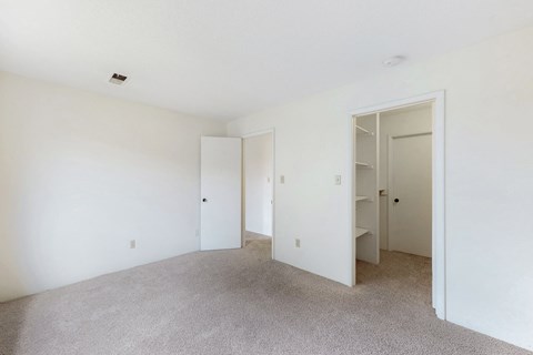 a bedroom with white walls and carpet and a closet