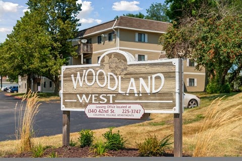 a sign for woodland west in front of a house