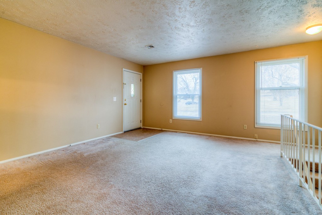 the living room of an empty house with a white staircase