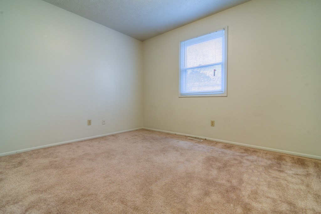an empty room with carpet and a window