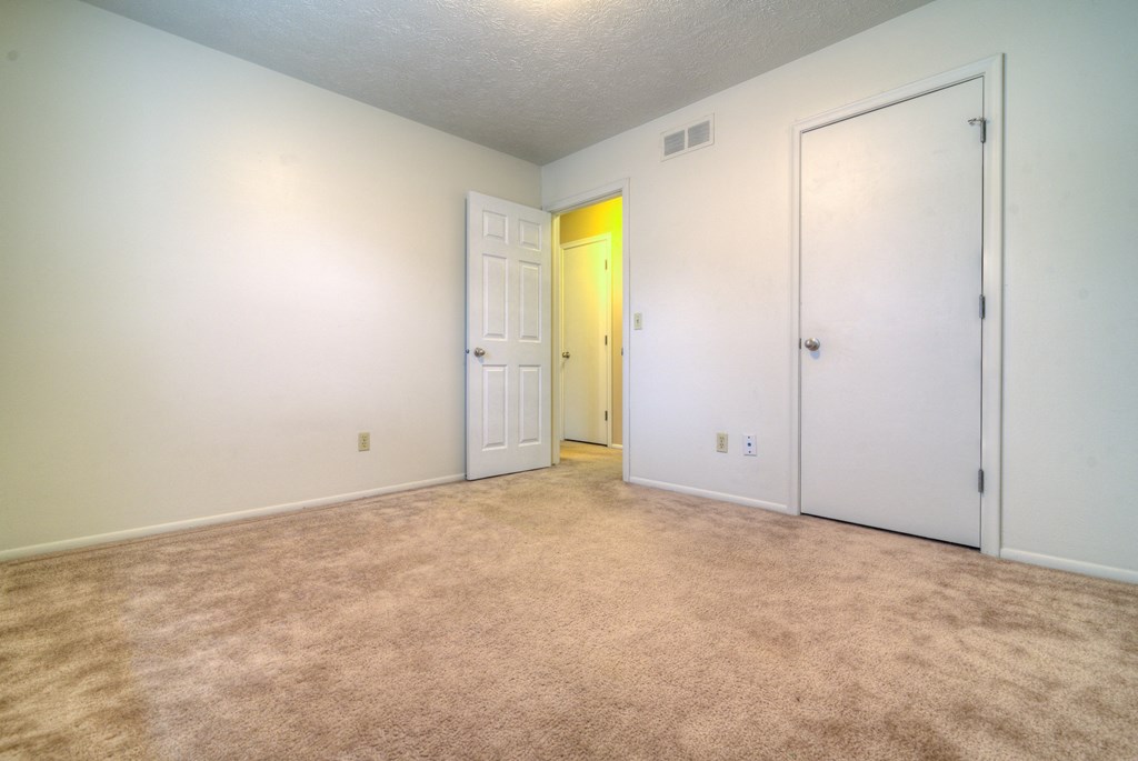 the living room of an empty home with white walls and a yellow door