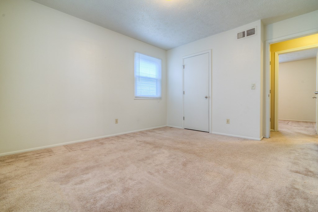 the living room of an empty house with a door and a window