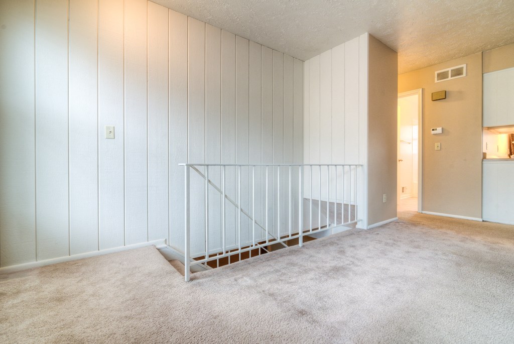an empty living room with white walls and a staircase