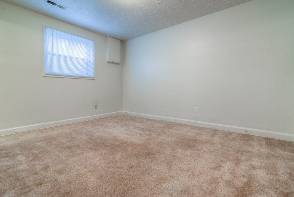 an empty room with carpet and a window