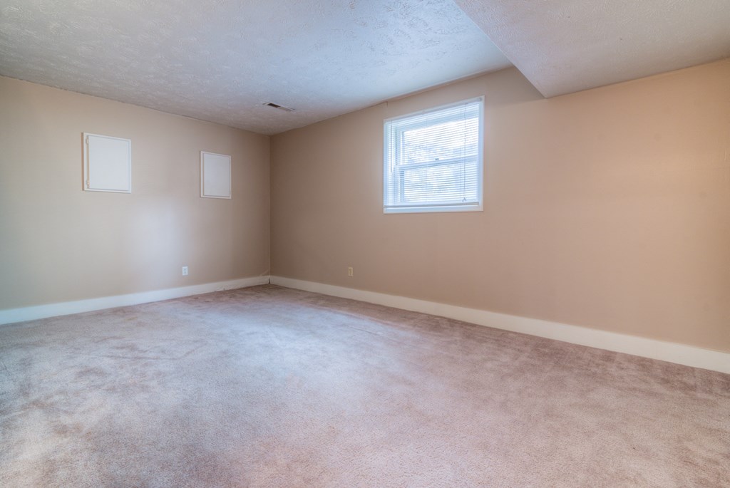 an empty living room with carpet and a window