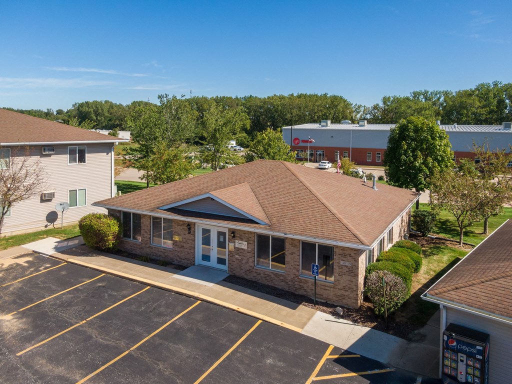 an aerial view of a brick building with a parking lot and trees