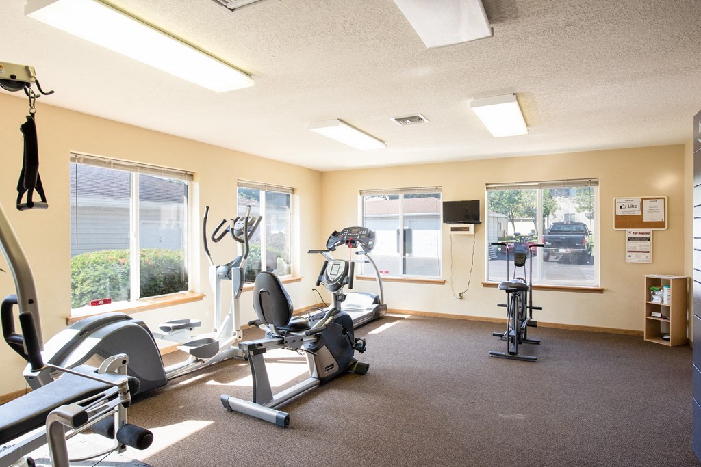 a gym with various exercise equipment and windows