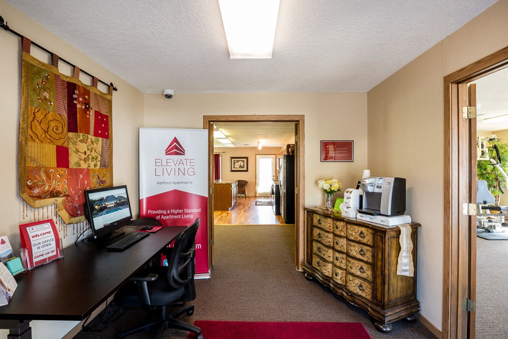 a room with a desk and a computer in it and a door to a hallway