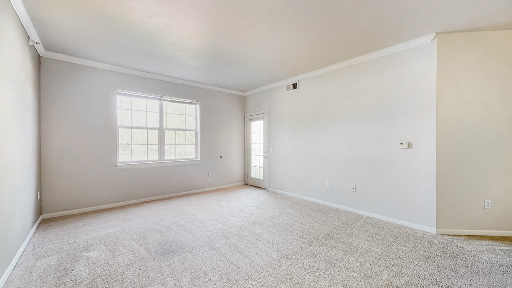 an empty living room with white walls and a window