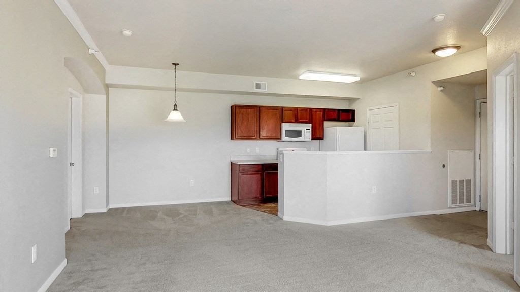the living room and kitchen of an empty apartment with white walls