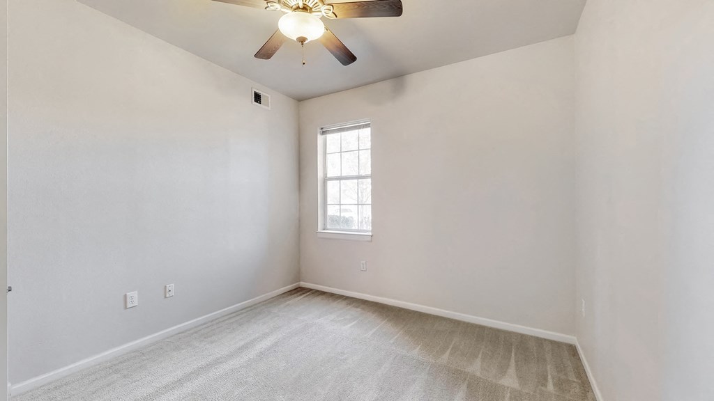 an empty living room with a ceiling fan and a window
