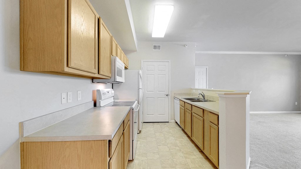 an empty kitchen with wooden cabinets and a white door