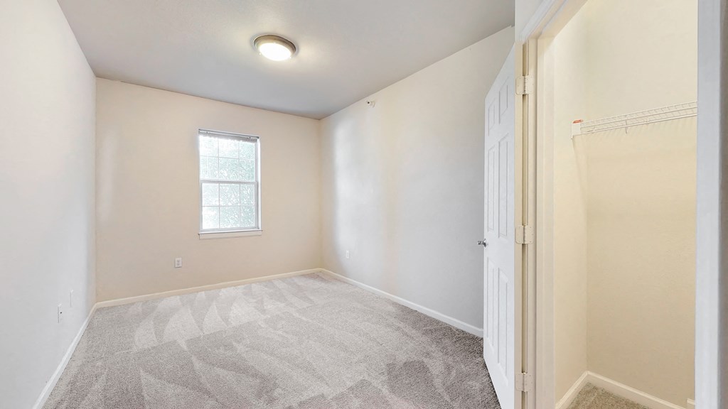 an empty room with a door to a closet and a window
