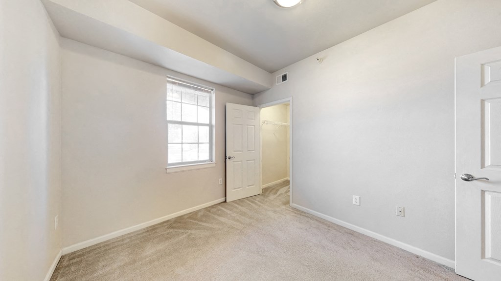 the living room and entryway of an empty home with white walls and a door