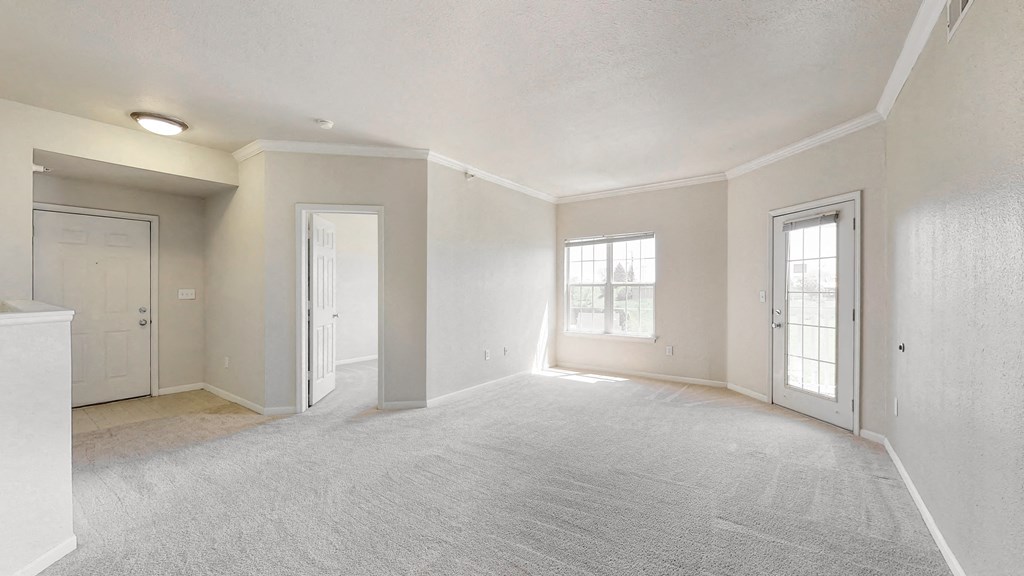 the living room and dining room of an empty home with white walls and carpet