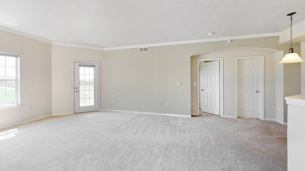 an empty living room with two doors and a carpeted floor