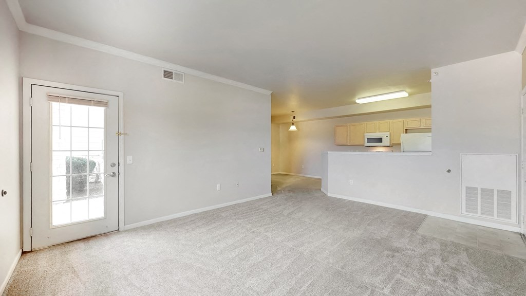 the living room and kitchen of an empty apartment with a glass door