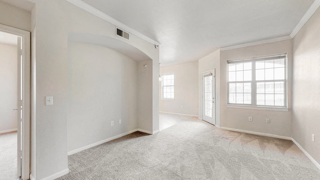 the living room and dining room of a new home with white walls and carpet