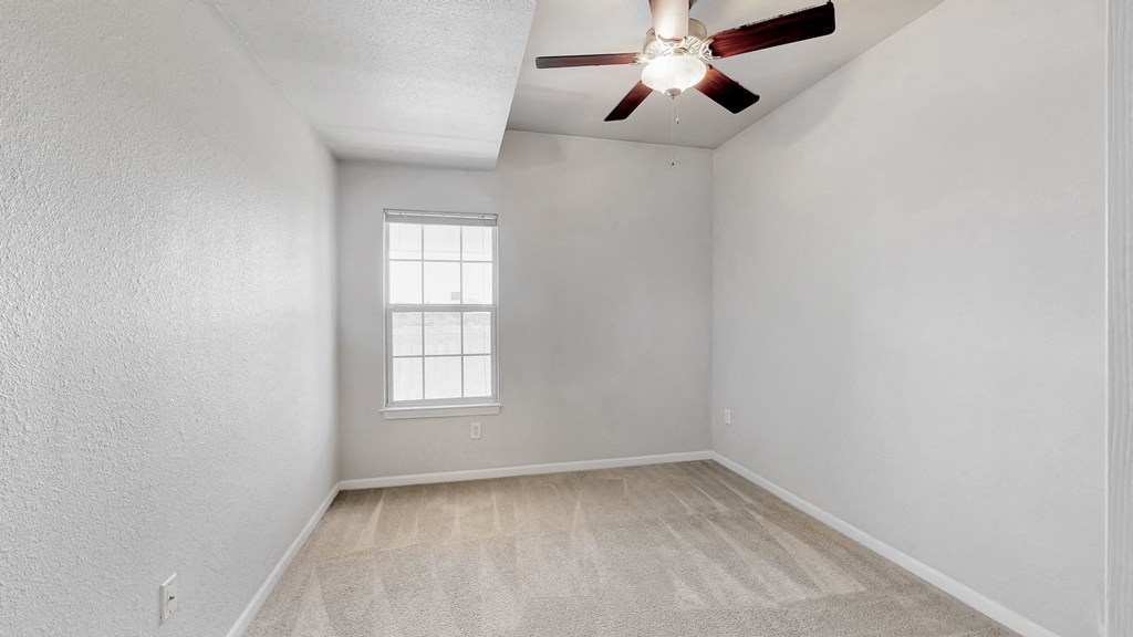 an empty room with a ceiling fan and a window