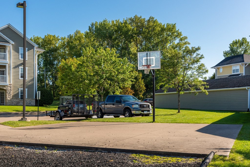 a truck parked next to a basketball hoop on the side of a street