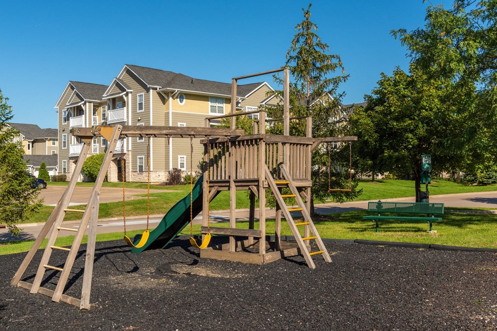 a swing set in a park with a house in the background