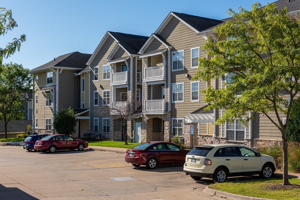 an apartment building with cars parked in a parking lot