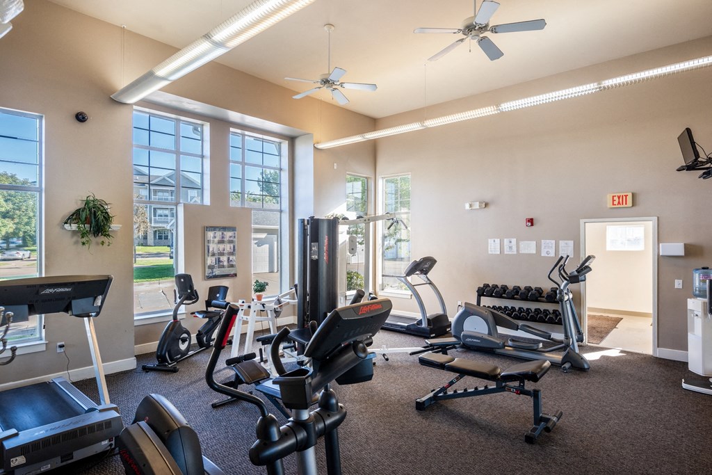 an exercise room with cardio equipment and large windows