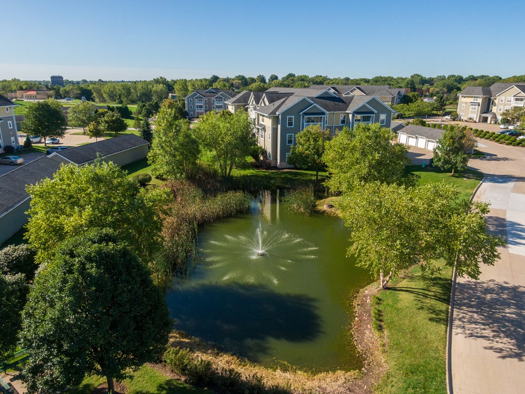 an aerial view of a pond with houses in the background