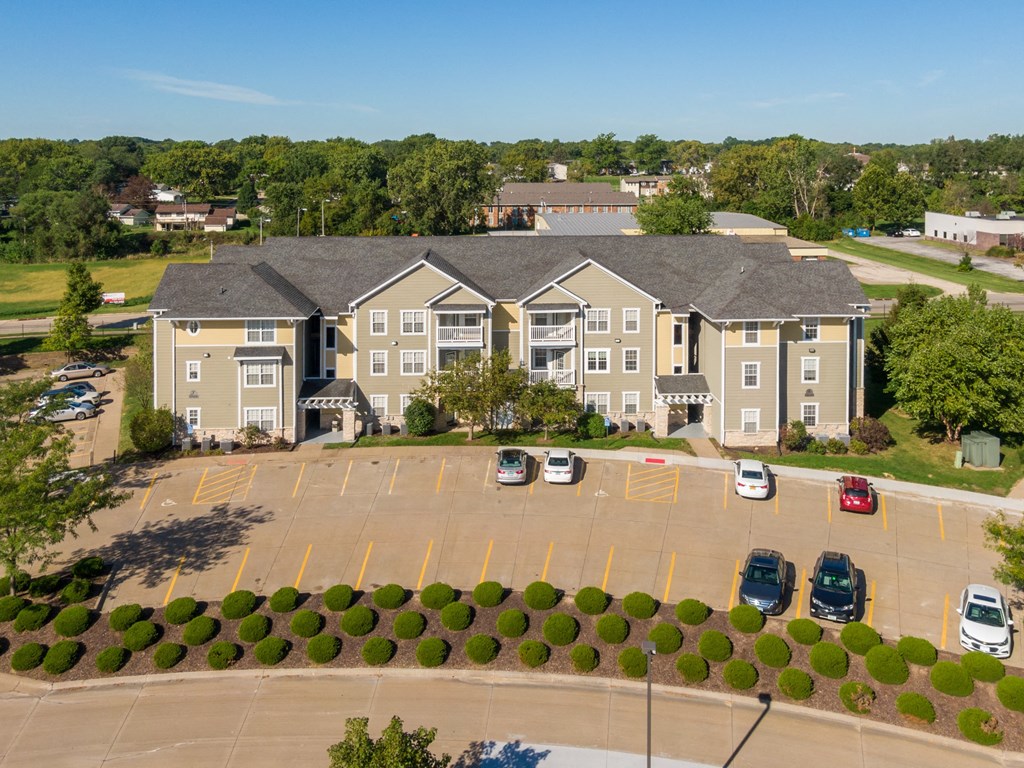 an aerial view of an apartment complex with parking lot and cars